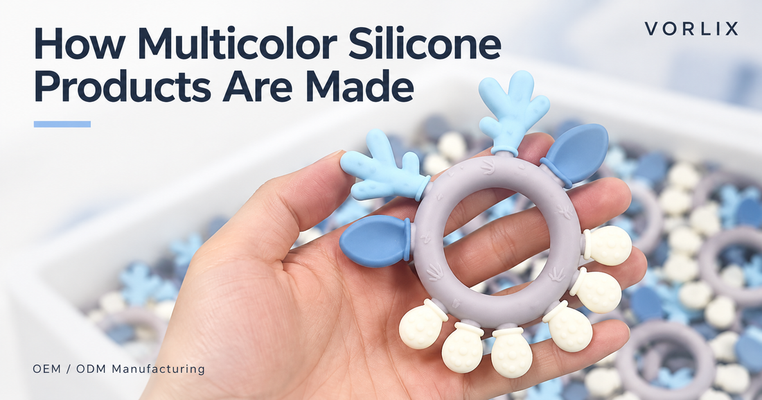 Hand holding a multicolor silicone ring with blue, lavender, and cream details, with a batch of matching products in the background on the VORLIX production floor.