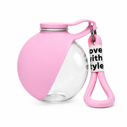 Pink portable pet water bottle with a foldable silicone drinking bowl and matching wrist strap for cats and dogs.