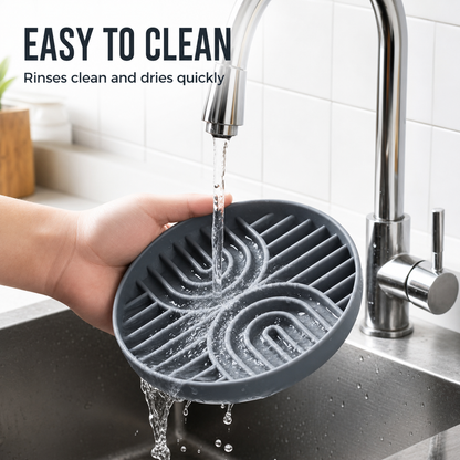 Gray silicone slow feeder dog bowl being rinsed under a kitchen faucet for easy cleaning